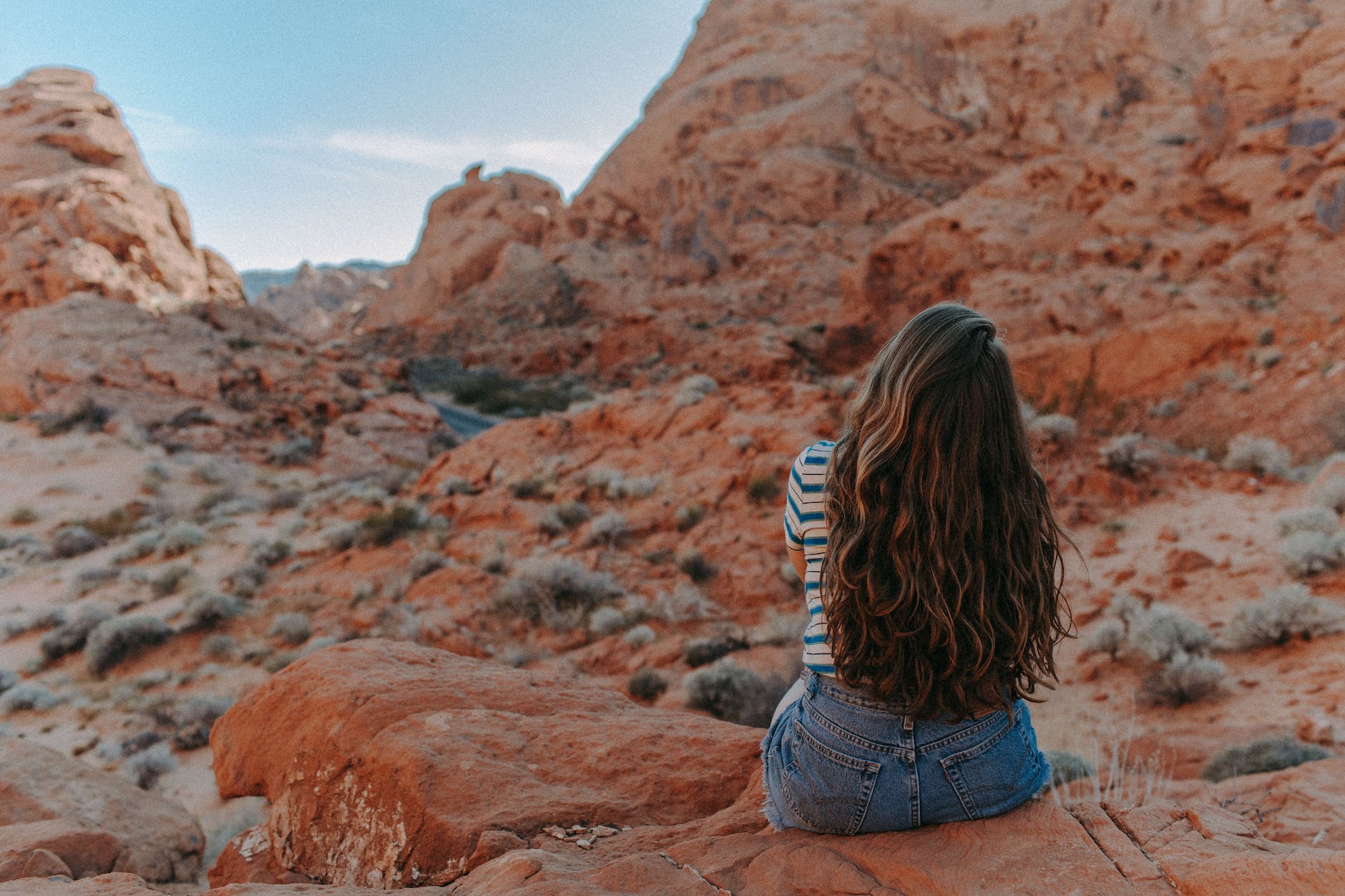 woman in blue denim shorts sitting on brown rock mountain