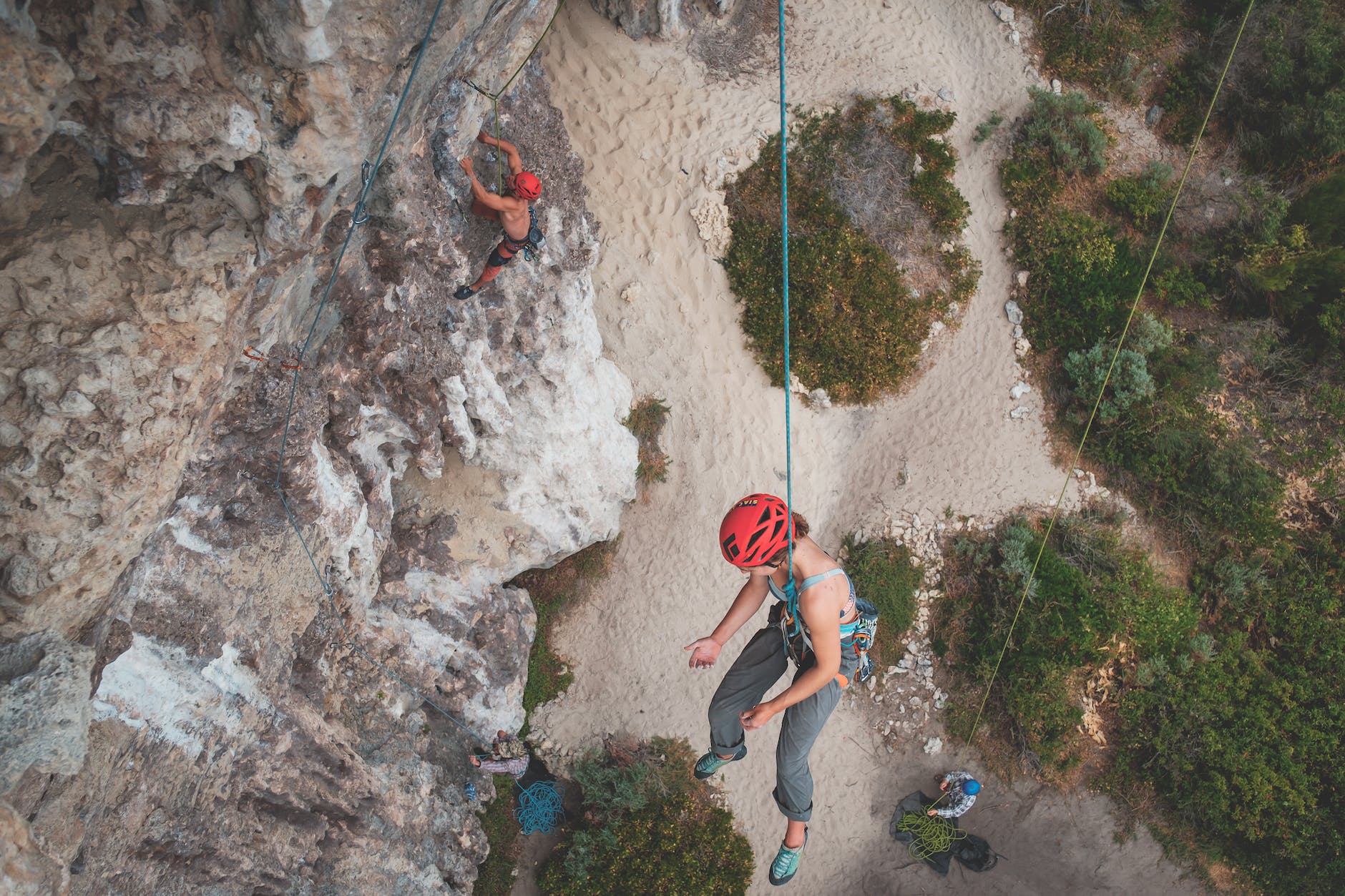 people in helmets with ropes climbing on rocky mountains
