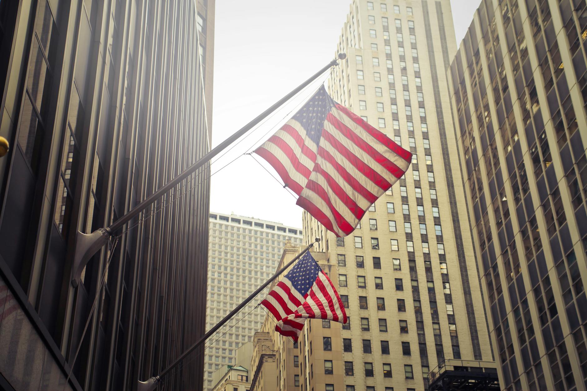 two u s a flags under white clouds at daytime